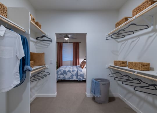 a walk in closet with shelves and racks and a bedroom with a bed
