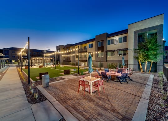 an outdoor patio with tables and chairs at night