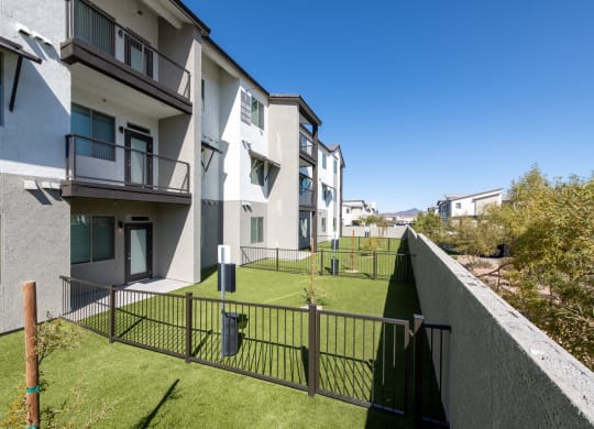 a view of an apartment complex with a green lawn and a fence