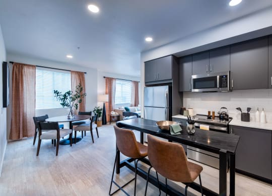 a kitchen with a island and a dining room with a table and chairs