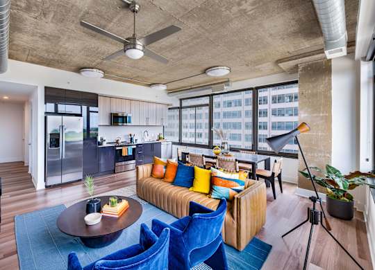 A living room with a blue couch and a ceiling fan.