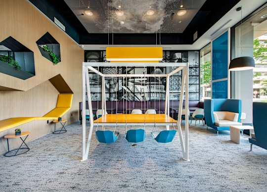 A modern room with a yellow swing and blue chairs.