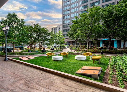 A park with a brick walkway, green grass, and trees.