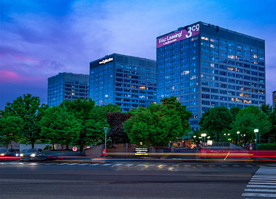 A cityscape at dusk with a large building that has a sign that says "Mace Leasing 3".