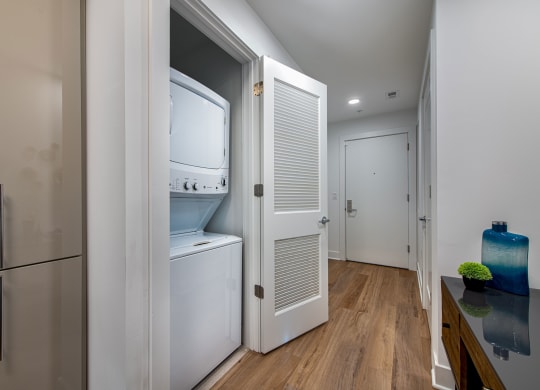 a small kitchen with a refrigerator and a washer and dryer in a closet