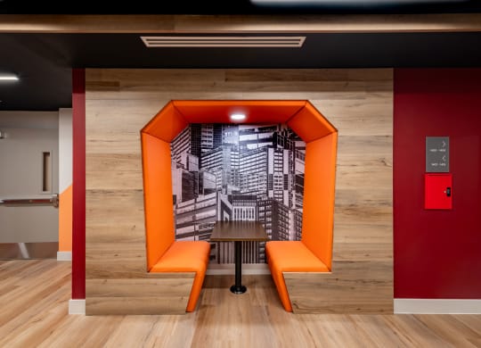 a staircase in a room with orange benches and a table