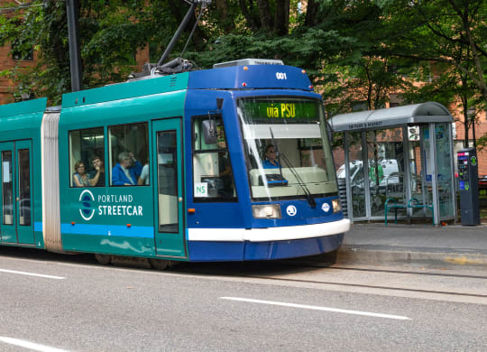 a blue tram is stopped at a bus stop