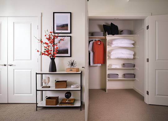 A white door is open to a hallway with a shelf and a vase on it.