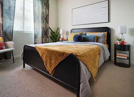 A bedroom with a large bed and a yellow blanket.