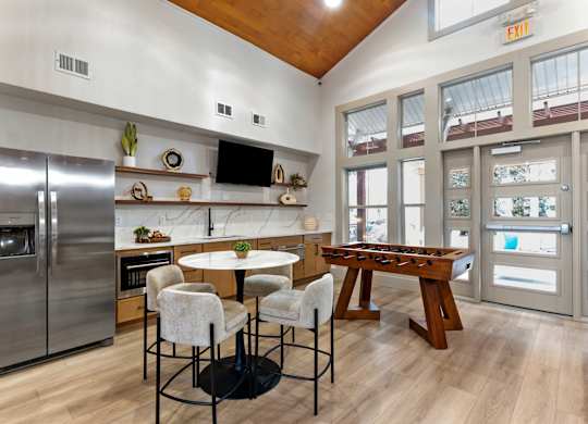 A kitchen with a refrigerator, a dining table, and chairs.