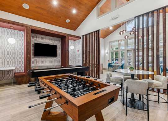 A shiny pool table is in the middle of a room with a bar and a television.