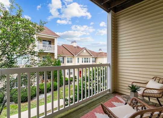 A balcony with a chair and a table overlooking a residential area.
