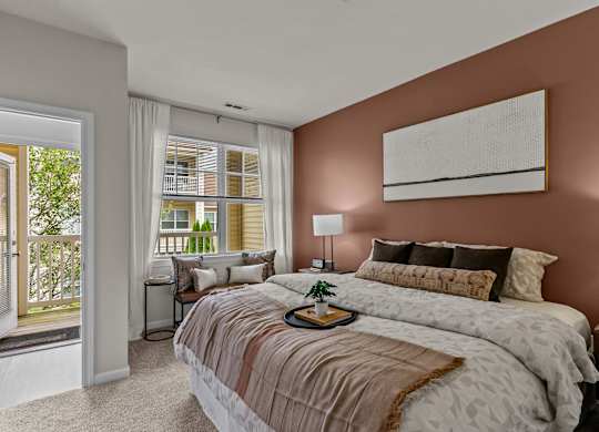 A bedroom with a large bed and a window overlooking a balcony.