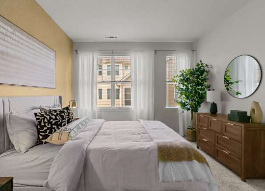A bedroom with a large bed, a dresser, and a mirror.