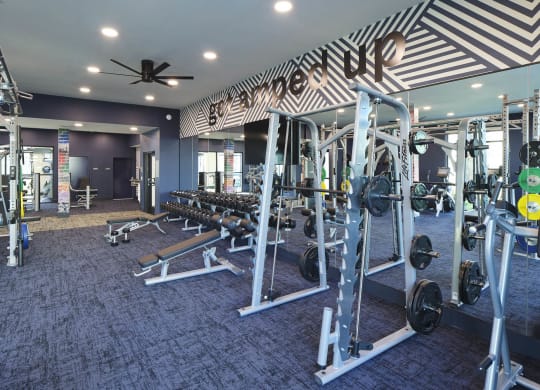 a gym with weights and a ceiling fan