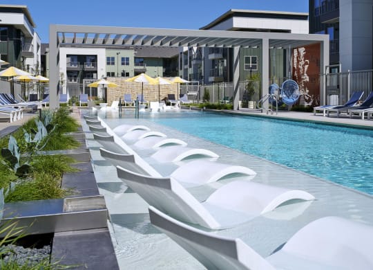 a pool with white chairs and a building in the background