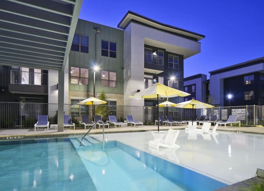 a pool with chairs and umbrellas in front of a building