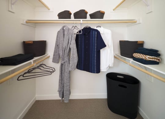 a walk in closet with wooden shelves and racks with clothes and baskets