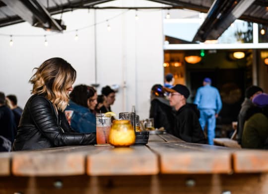 a woman sitting at a table in a bar with a drink