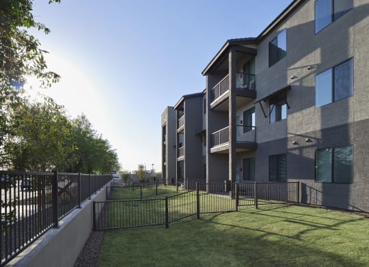 an apartment building with a yard and a fence