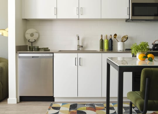 a small kitchen with white cabinets and a table