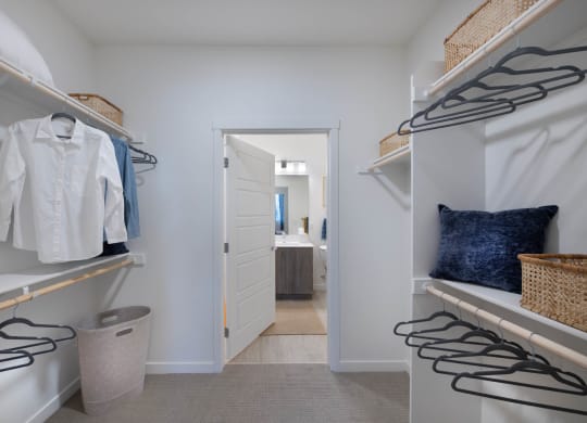 a walk in closet with white closets and a door to a bathroom