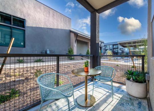 a patio with blue chairs and a table on a balcony