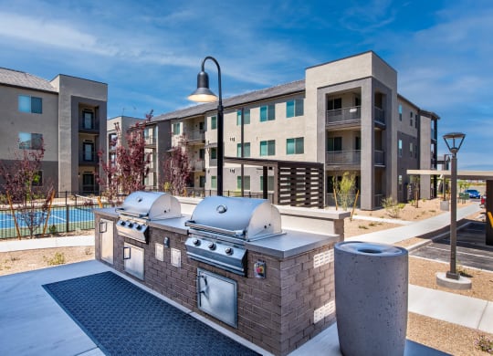 an outdoor grill area with apartments in the background
