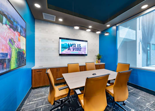 a conference room with a table and chairs and a tv
