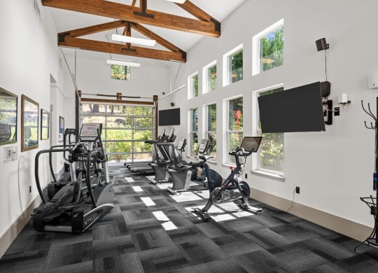 the gym has treadmills and other exercise equipment and windows