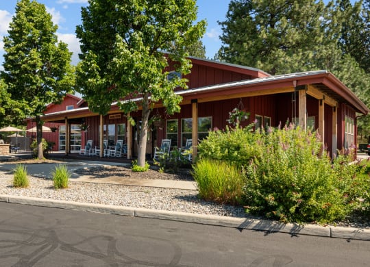 the front of a red building with trees and a street