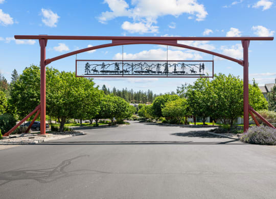 the arch at the end of a road with trees and a driveway