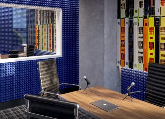 a desk with a laptop and microphone in a room with a window