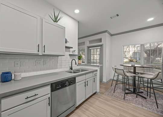 A modern kitchen with white cabinets and a wooden floor.