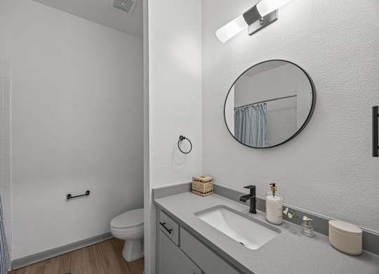 A bathroom with a toilet, sink, and mirror.
