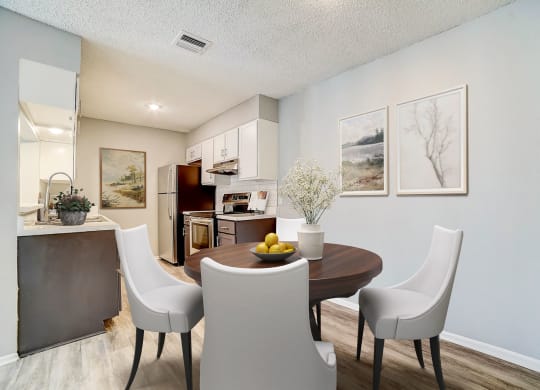 a dining area with a table and chairs and a kitchen in the background