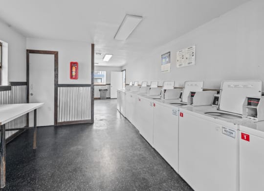 a laundry room with white walls and a black tiled floor
