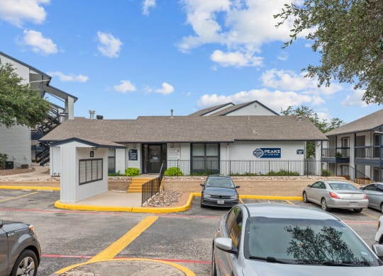 a white building with a gray roof and a parking lot in front of it