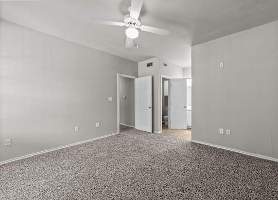 A room with a ceiling fan and carpeted floor.