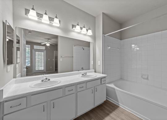 A bathroom with a white tub, sink, and mirror.
