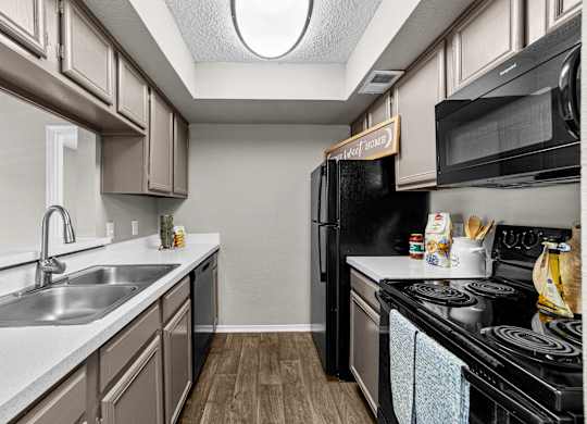 A kitchen with a black refrigerator and a white sink.