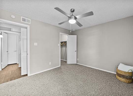 A room with a ceiling fan and a carpeted floor.