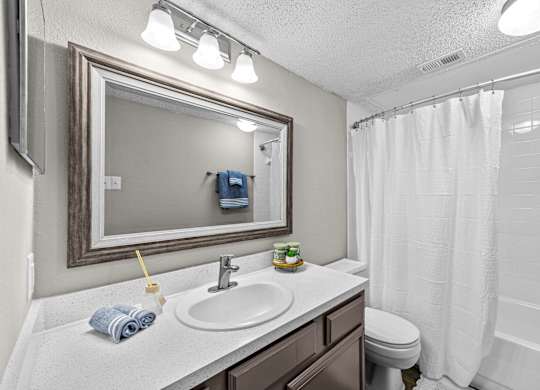 A bathroom with a white sink, toilet, and shower curtain.