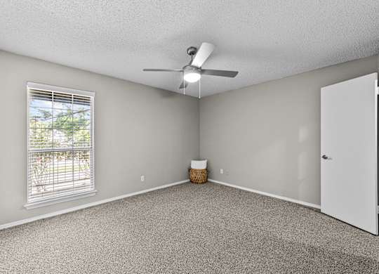 A room with a ceiling fan and a window with blinds.
