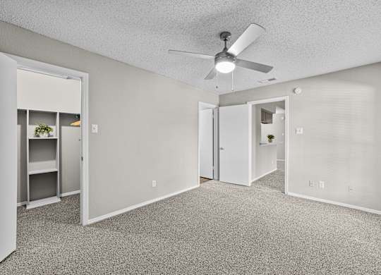 A room with a ceiling fan and carpeted floor.
