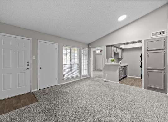 A spacious kitchen and living room with white appliances and a grey refrigerator.