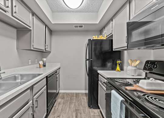 A kitchen with a black refrigerator and stove top oven.