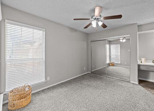 A room with a ceiling fan and a mirror on the wall.