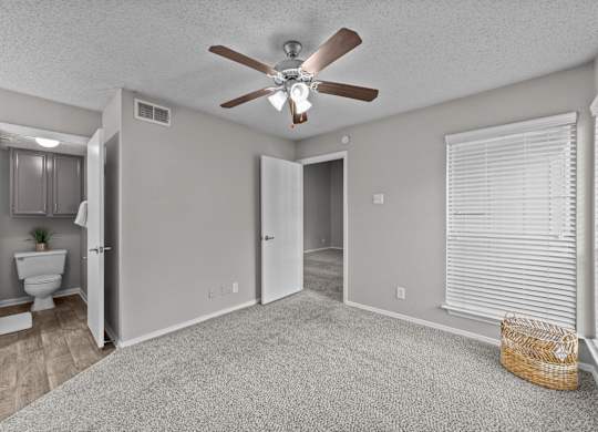 A room with a ceiling fan and a carpeted floor.