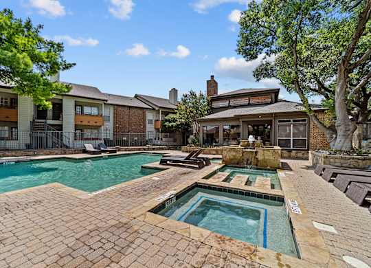 A large outdoor swimming pool with a hot tub in the middle.